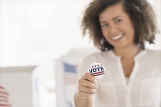 Young woman holding voting badge and smiling.