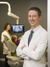 Portrait of dentist with colleague and patient (8-9) in background
