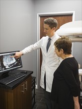 Dentist showing patient x-ray on computer screen