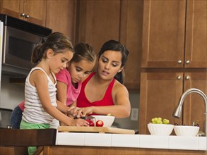 Mother and children (6-7, 8-9) preparing food in kitchen