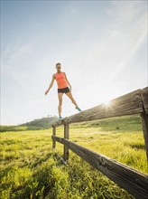Woman balancing on wooden fence