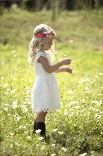 Cute girl (4-5) in white dress standing in meadow