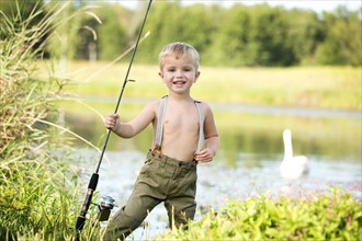Smiling boy (4-5) holding fishing rod