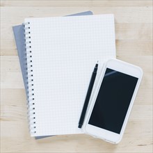 Overhead view of pen and smart phone on notebook