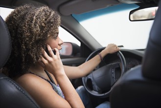 Young woman using phone while driving car.