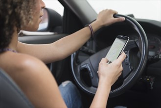 Young woman texting while driving car.