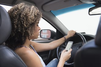Young woman texting while driving car.
