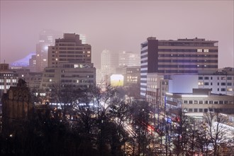 Illuminated cityscape in fog