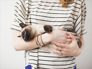 Woman holding Siamese cat