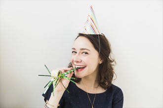 Smiling young woman with party horn blower