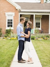 Young couple standing on footpath in front of house