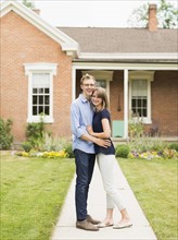 Young couple standing on footpath in front of house