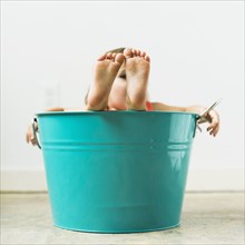 Little girl (2-3) sitting in turquoise bucket