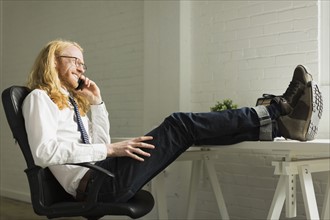Man talking on phone with feet up on desk