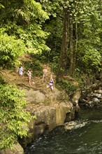 Women swinging on rope swing above river in distance