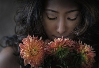 Young woman smelling flowers.
