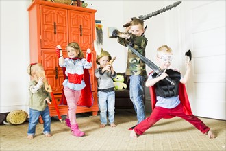 Children (2-3, 4-5, 6-7) wearing superhero costumes playing at home