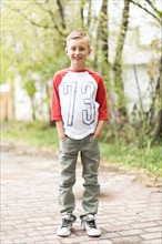 Portrait of boy (6-7) standing on sidewalk