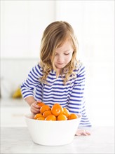 Girl (4-5) looking at oranges, smiling