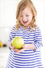 Girl (4-5) looking at apples, laughing