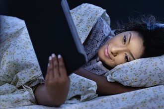 Young woman using tablet in bed.