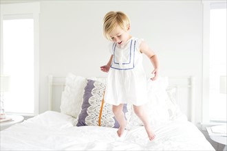 Girl (2-3) jumping on bed