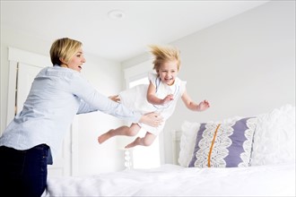 Woman playing with girl (2-3) in bedroom