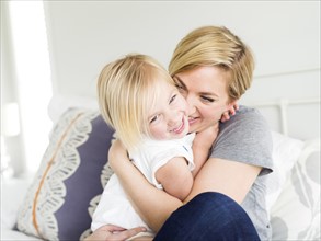 Woman hugging daughter (2-3) in bedroom