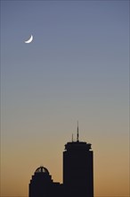 Crescent moon above office buildings