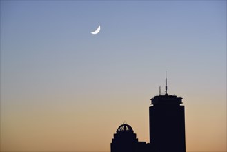 Crescent moon above office buildings