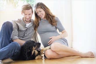 Couple relaxing with dog on floor.