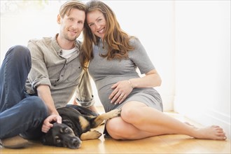 Portrait of mid-adult couple with dog indoors.