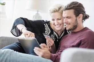 Couple using tablet pc on sofa.