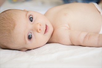 Baby girl (2-5 months) lying on bed