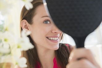 Woman using hand mirror at home