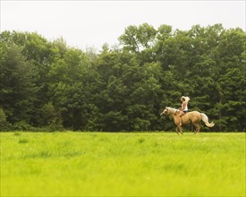 Woman horseback riding in countryside