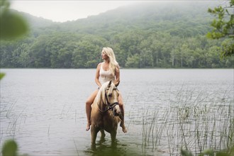 Woman horseback riding in countryside