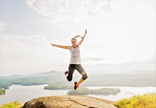 Young woman jumping over mountain top