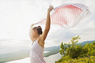 Young woman holding scarf on wind against lake view