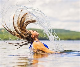 Young woman tossing hair back in lake