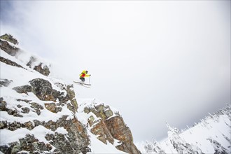 Skier jumping off rocky mountain