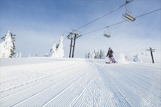 Mid-adult woman on ski slope under cable car