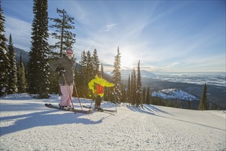 Couple standing on ski slope at sunlight