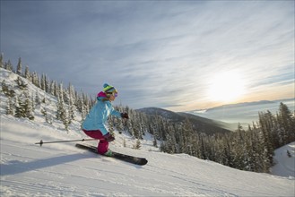 Mature woman on ski slope at sunset