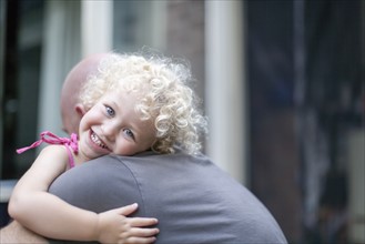 Smiley daughter (4-5) hugging father