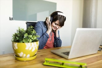 Young woman listening to music in office