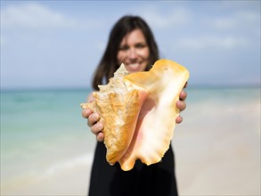 Woman holding seashell on beach