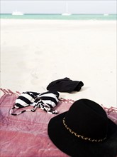 Bikini and sunhat on blanket on beach