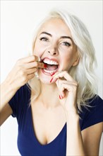 Studio shot of woman using dental floss
