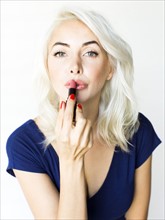 Studio shot of woman using lipstick